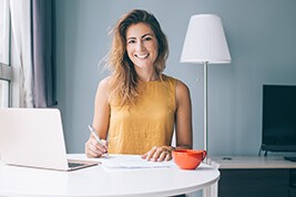 Lächelnde Frau am Tisch mit Laptop